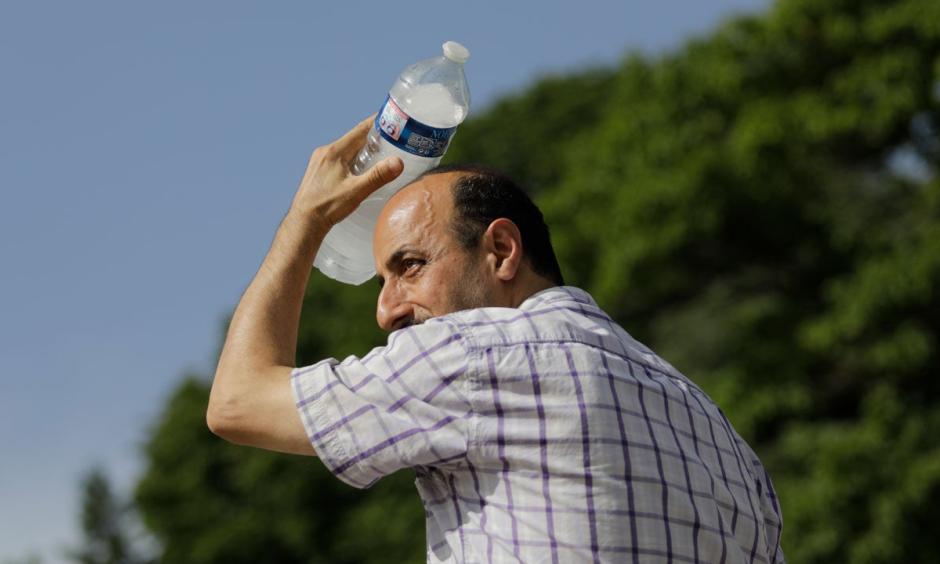 A man uses a cool bottle of water to cool off in the Trocadero gardens in Paris, Friday, June 28, 2019. Credit: Lewis Joly, AP