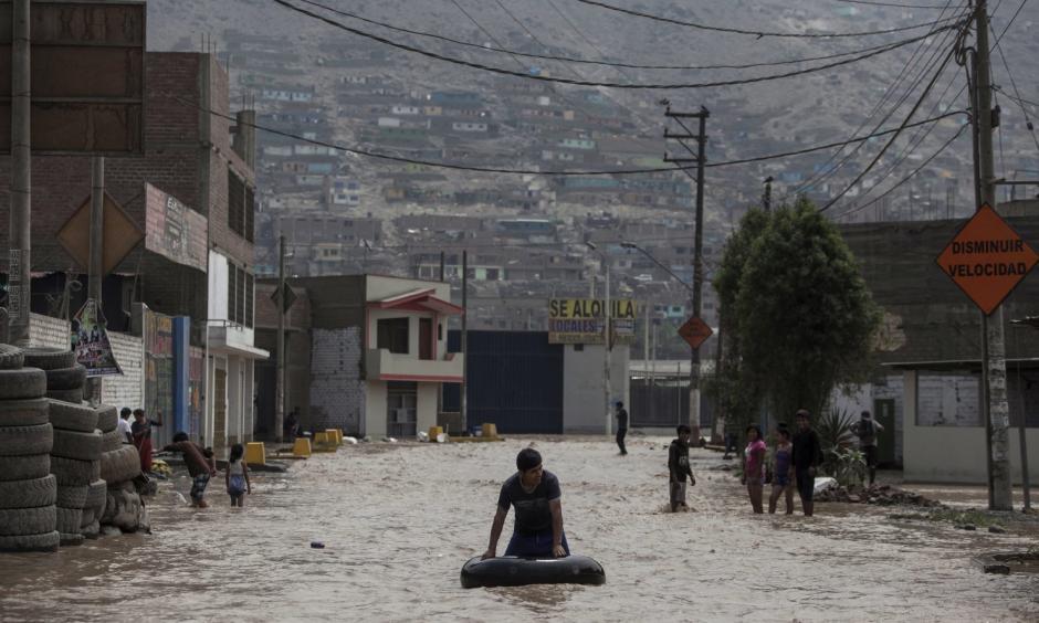 A man plays in a flooded street using an inner tube in Lima, Peru, Thursday, March 16, 2017. A new round of unusually heavy rains has killed at least a dozen people in Peru and now threatens flooding in the capital. Authorities said Thursday they expect the intense rains caused by the warming of surface waters in the eastern Pacific Ocean to continue another two weeks. Photo: Rodrigo Abd, Associated Press