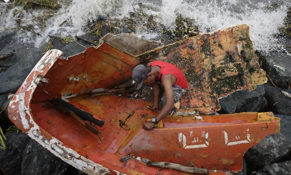 Filipino Joybin Marayo, 58, salvages metals on a damaged boat that was washed ashore by strong waves brought about by Typhoon Haima in Manila, Philippines on Thursday Oct. 20, 2016. Photo: Aaron Favila