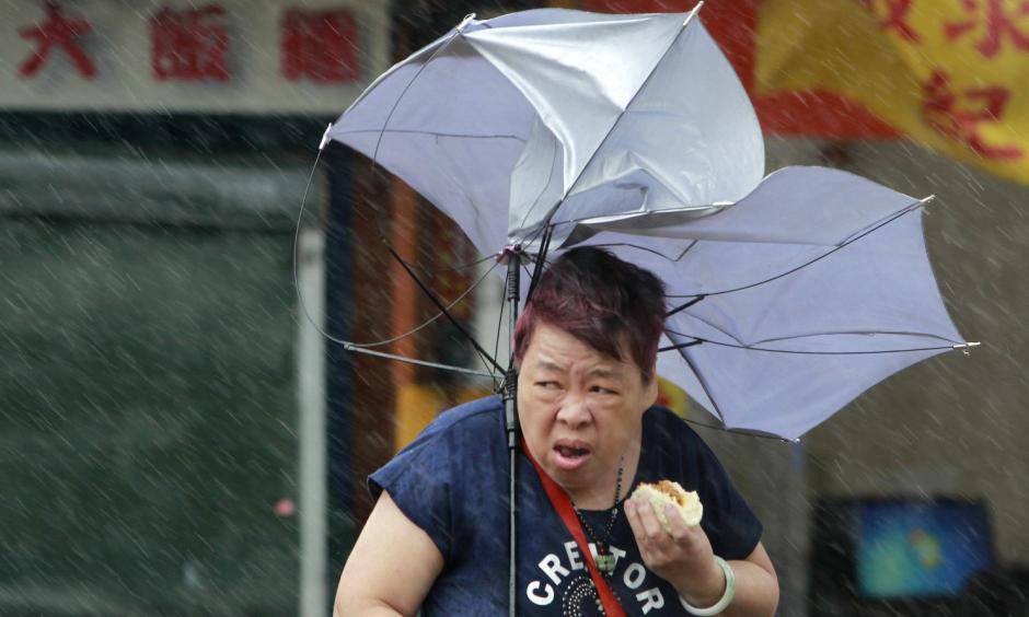 A woman eats and struggles with her umbrella against powerful gusts of wind generated by typhoon Megi across the the island in Taipei, Taiwan, Tuesday, Sept. 27, 2016. Schools and offices have been closed on Taiwan and people in dangerous areas have been evacuated as a large typhoon with 162 kilometers- (100 miles-) per-hour winds approaches the island. Photo: Chiang Ying-ying, Associated Press
