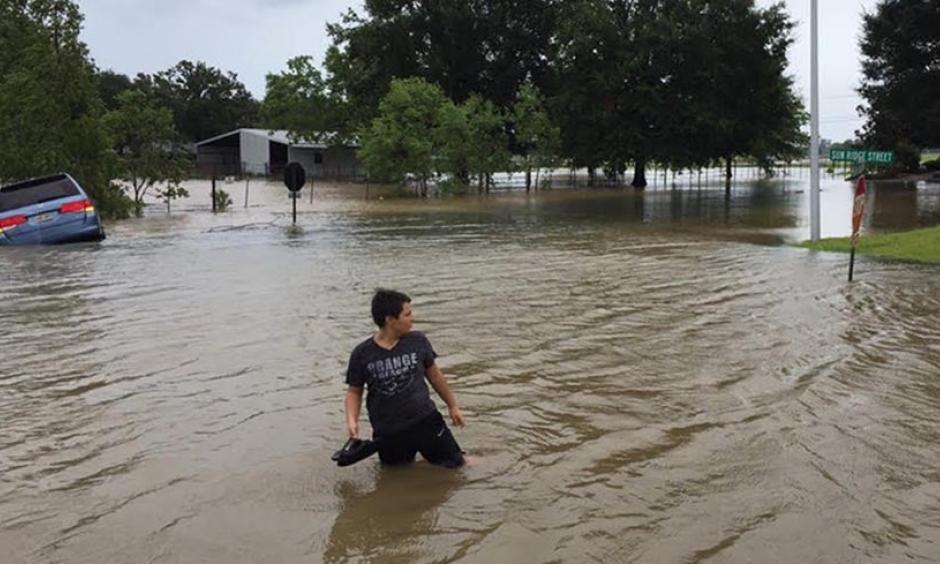 A person wades in floodwaters as a van is overtaken by water in a Youngsville, Louisiana neighborhood on Sunday, July 14, 2019, during Tropical Storm Barry. Credit: Mark Hargrave