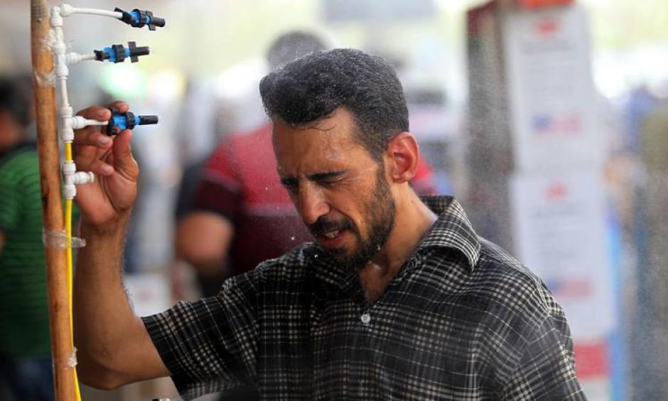 An Iraqi man using an atomizer made available for people outside a shop selling cooling and ventilation products on July 20, the first day of a two-day holiday for government employees Iraqi authorities announced due to the heat. Photo: Ahmad Al-Rubay, Agence France-Presse