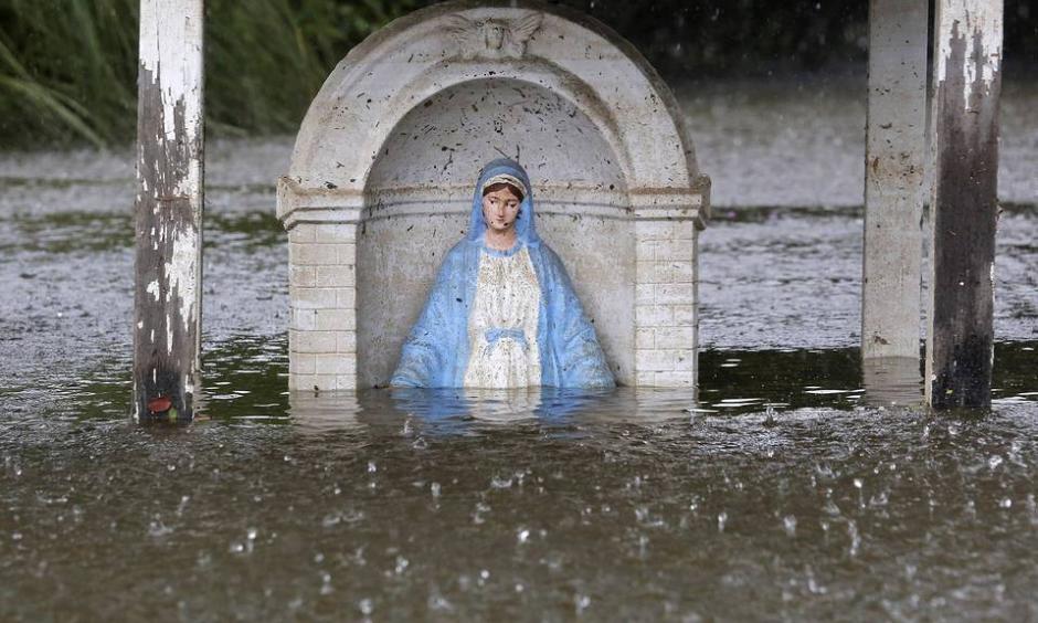A statue of the Virgin Mary is seen partially submerged in flood water as it rains in Sorrento, La., Saturday. Photo: Reuters
