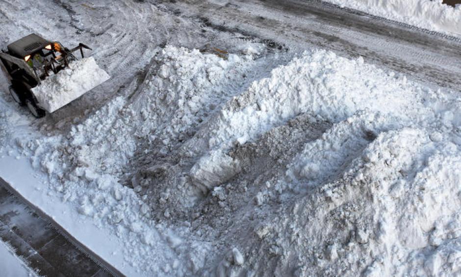 A Bobcat adds to a growing snow pile on Monument Street as it is removed from the 700 block of Calvert Street on Monday morning following the weekend snowstorm. Photo: Jerry Jackson, Baltimore Sun)