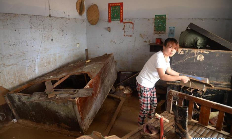 A villager clears the debris at her home in Nanshitun village of Xingtai City, north China's Hebei Province, July 24, 2016. Torrential rain and floods have left 34 people dead and 13 people missing in Xingtai City by Sunday as well as some 9,200 homes were still without electricity. Photo: Xinhua