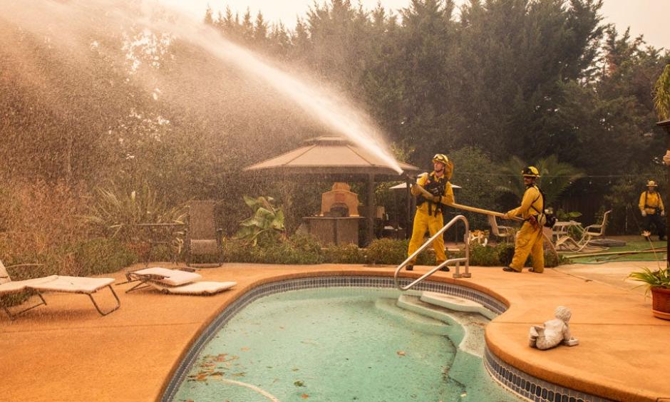 Firefighters spray water on a spot fire at a home during the Kincade Fire on Vinecrest Road in Windsor, Calif., on Sunday, Oct. 27, 2019. Credit: The Weather Channel