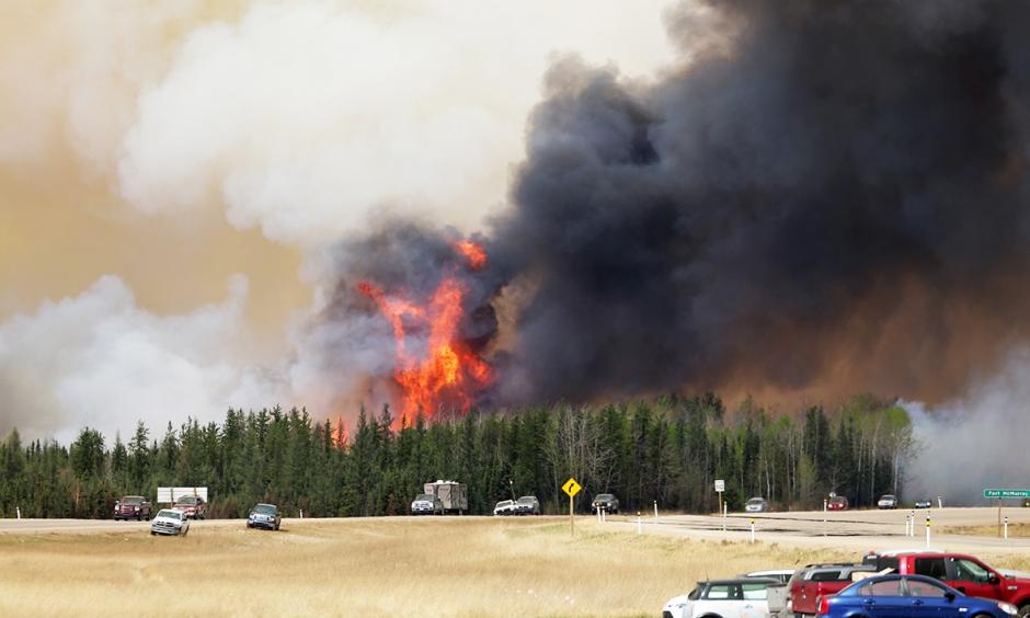 A convoy of evacuees drives south as flames and smoke rise along the highway near Fort McMurray, Alberta, on May 6. Photo: Getty Images