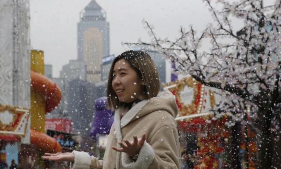 A visitor enjoys the artificial snow made of foam at a carnival in Hong Kong, on Jan. 26, 2016. In Hong Kong, the mercury dipped to its lowest in six decades. Photo: Kin Cheung, AP