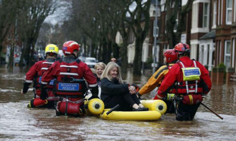 Emergency workers use an inflatable raft to rescue two women from flooding. Photo: BBC