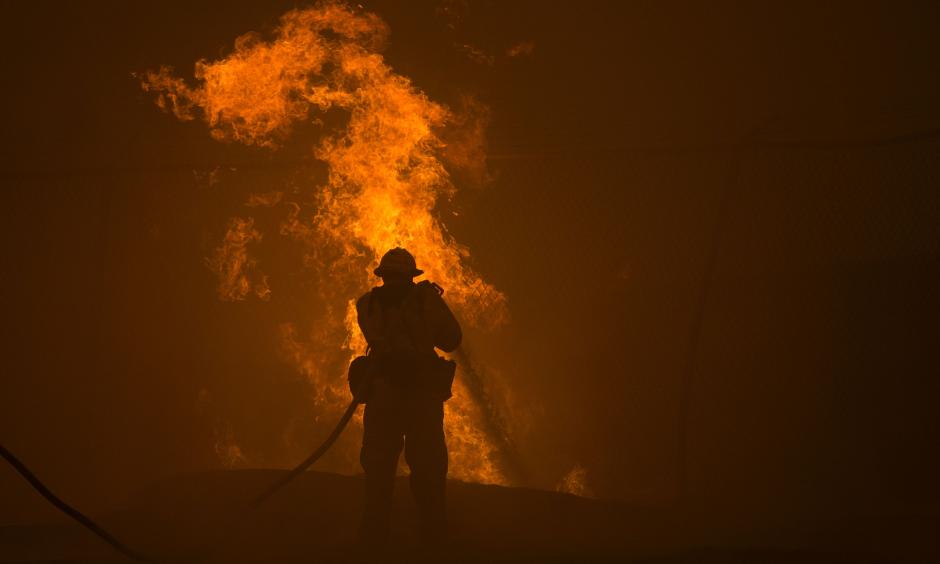 A firefighter hosed down burning pipes on Saturday near Santa Clarita, Calif. Photo: David McNew / Agence France-Presse — Getty Images