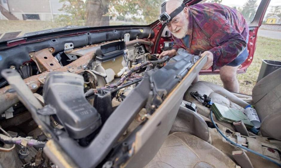 Arthur Knight works on his Lexus, which was damaged in the flooding outside of this home on Railroad Street in Milesburg. Photo: Abby Drey