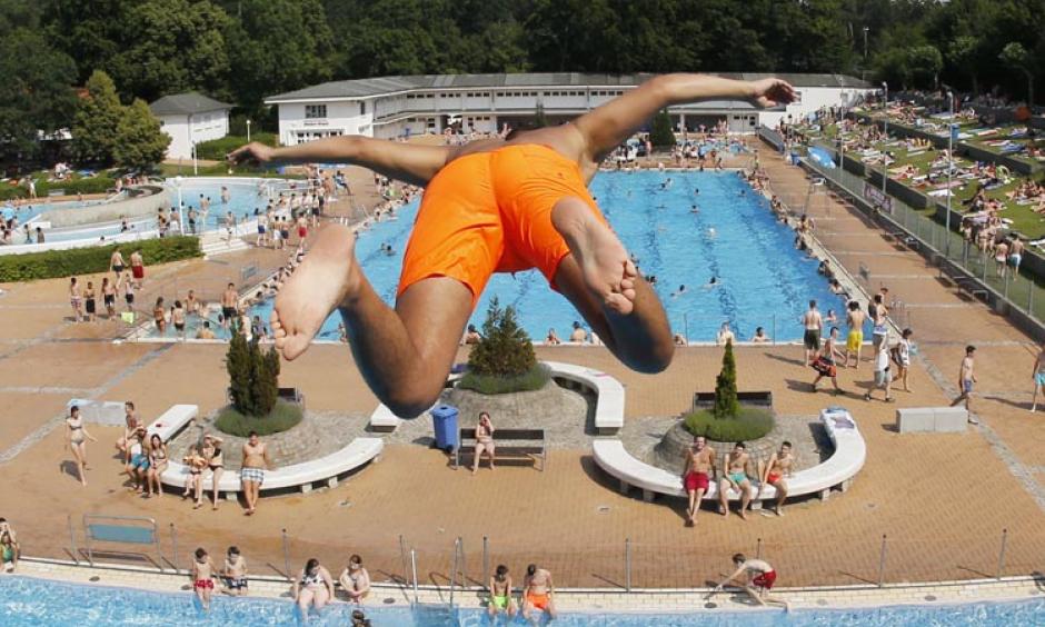 A young boy jumps from a 7.5 meter platform at a crowded outdoor pool during a record heat wave in Frankfurt, Germany, Friday, July 3, 2015. Photo: Michael Probst, AP