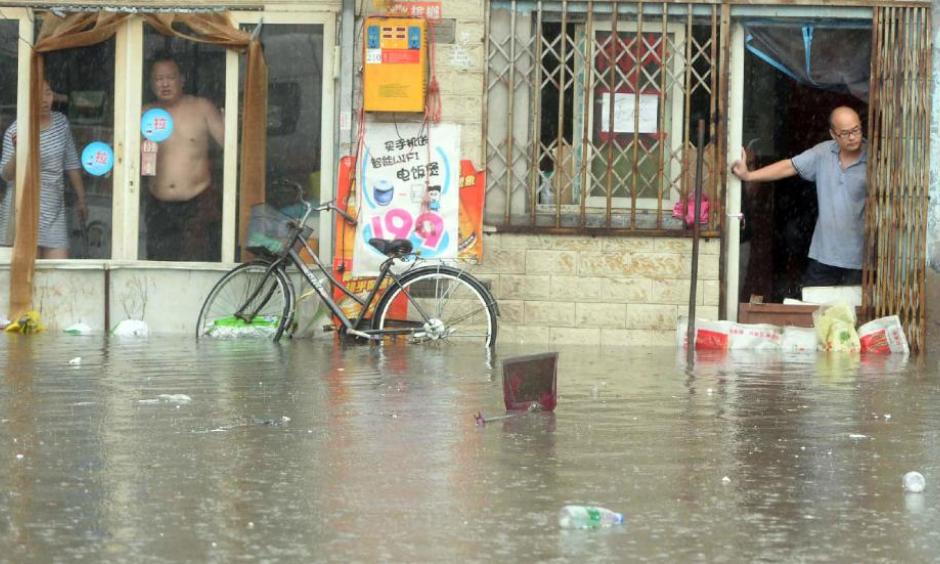 Chinese residents look at a flooded area caused by heavy rain in Beijing on July 20, 2016. Photo: STR/AFP/Getty Images