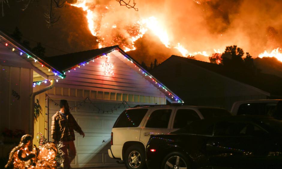 A man prepares to evacuate his home as a wildfire burns along a hillside near homes in Santa Paula, California. Photo: Ringo Chiu, AFP/Getty Images