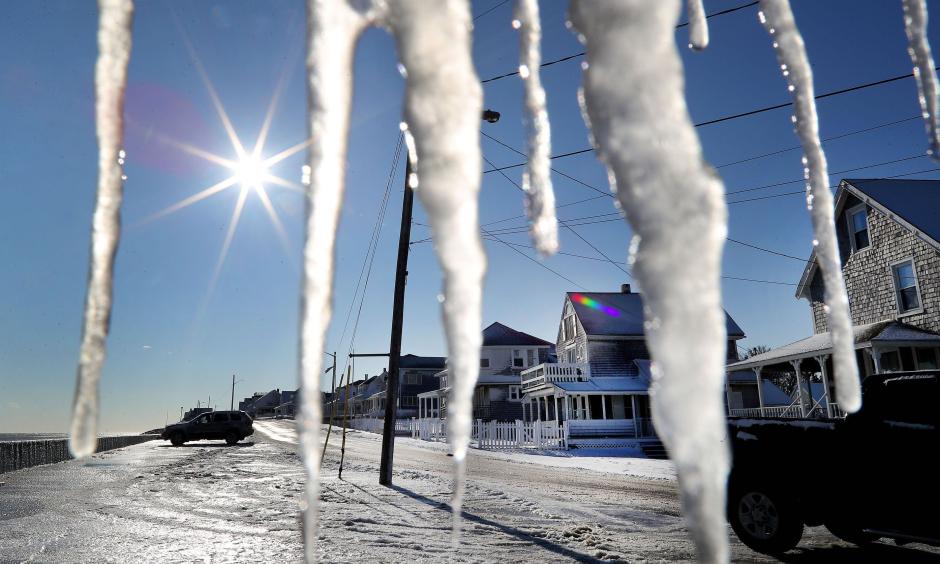 Icicles hang from a porch on Ocean Street as cleanup takes place in the Brant Rock section of Marshfield, MA, following a winter storm that flooded much of the area the previous day, on Jan. 5, 2018. Photo: John Tlumacki, The Boston Globe via Getty Images
