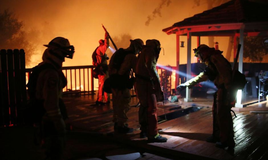 Firefighters work to save a home from an encroaching fire during the Lilac fire in Bonsall, California on Thursday, December 7, 2017. Credit: Sandy Huffaker, AFP, Getty Images