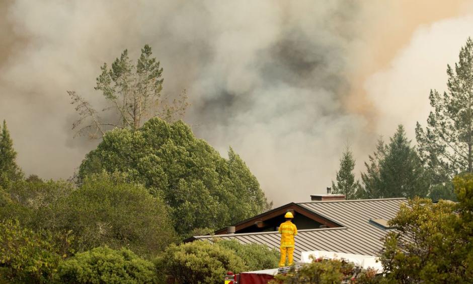A firefighter watches smoke billow as flames approach a residential area in Sonoma in California in October. Photo: Josh Edelson, AFP/Getty Images