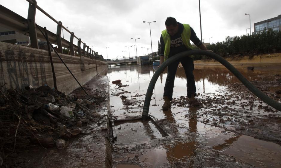 A worker tries to clean a sewer as water covers an interchange of a highway in Elefsina, western Athens, on Wednesday, Nov. 15, 2017. Flash floods in the Greek capital’s western outskirts Wednesday converted roads into raging torrents of mud and debris, killing at least five people and inundating homes and businesses. Photo: Petros Giannakouris/Associated Press