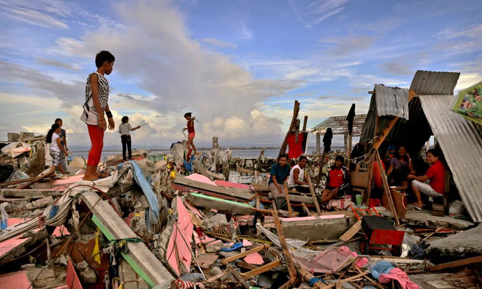 Residents gather amongst the devastation in the aftermath of Typhoon Haiyan on November 13 in Tacloban, Leyte, Philippines. Typhoon Haiyan, packing maximum sustained winds of 195 mph (315 kph), slammed into the southern Philippines and left a trail of destruction in multiple provinces, forcing hundreds of thousands to evacuate and making travel by air and land to hard-hit provinces difficult. Photo: Kevin Frayer, Getty Images