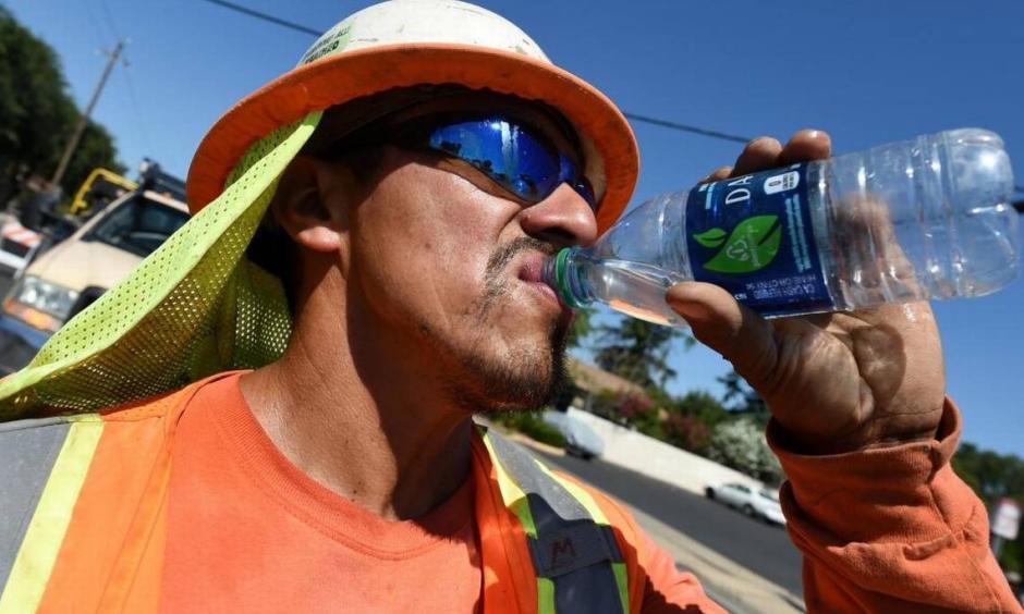 Miguel Lunar of Madco Electric takes a swig of cold water during work at Palm and Shields avenues to install traffic sensors under the roadway surface on June 21. Photo: John Walker, Fresno Bee
