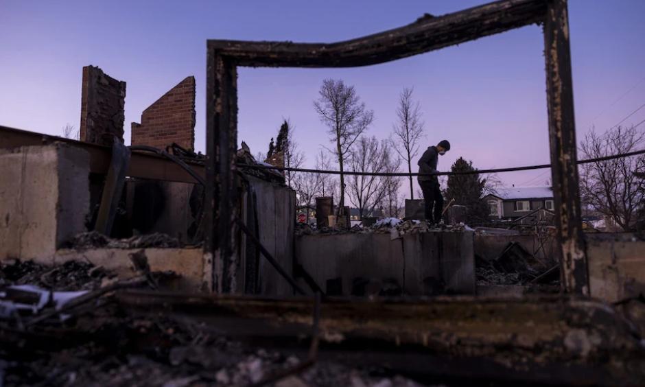 A man digs through debris at his parent's home in a neighborhood decimated by the Marshall Fire on Jan. 2 in Louisville, Colo. Officials reported that 991 homes were destroyed in the blaze, making it the most destructive wildfire in Colorado history. (Michael Ciaglo/Getty Images)