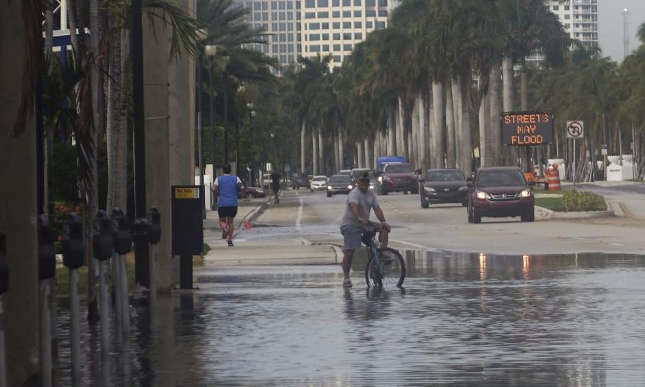 A bicyclist stops to negotiate Las Olas Boulevard, flooded by an unusually high tide known as a king tide, in Fort Lauderdale on Monday. Photo: Joe Cavaretta, South Florida Sun-Sentinel via Associated Press