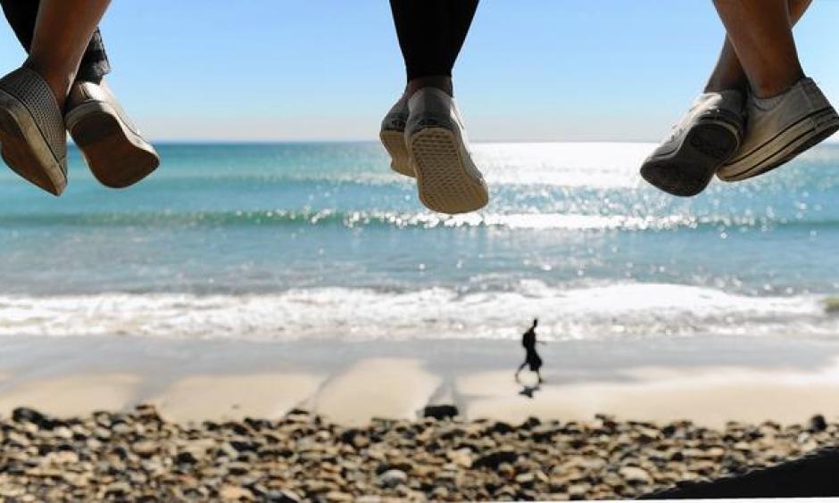 On a hot winter day in Malibu, three young girls dangle their feet from a lifeguard tower on Pacific Coast Highway. Photo: Wally Skalij, Los Angeles Times