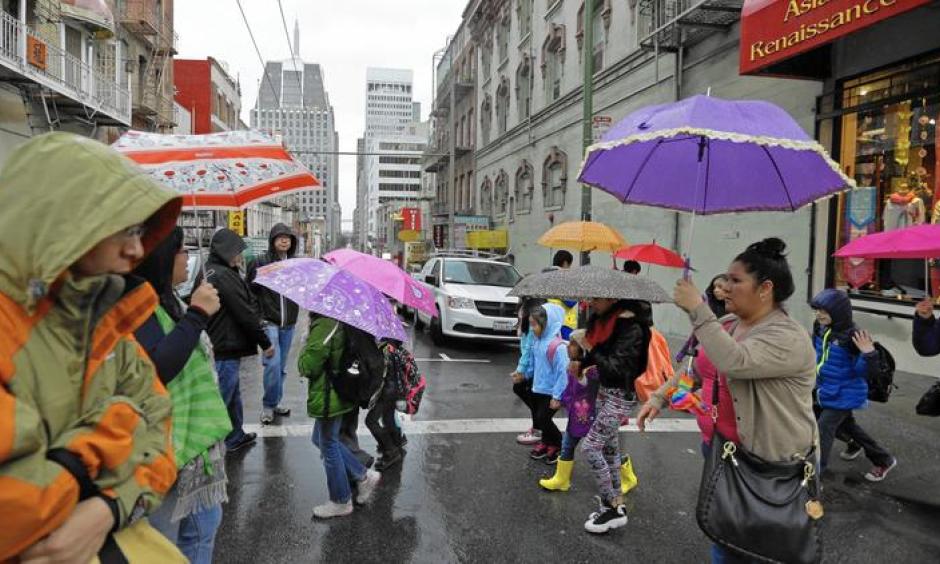 Pedestrians take cover in the Chinatown district of San Francisco as a powerful storm rolled into the Bay Area. Image: Ben Margot / Associated Press)
