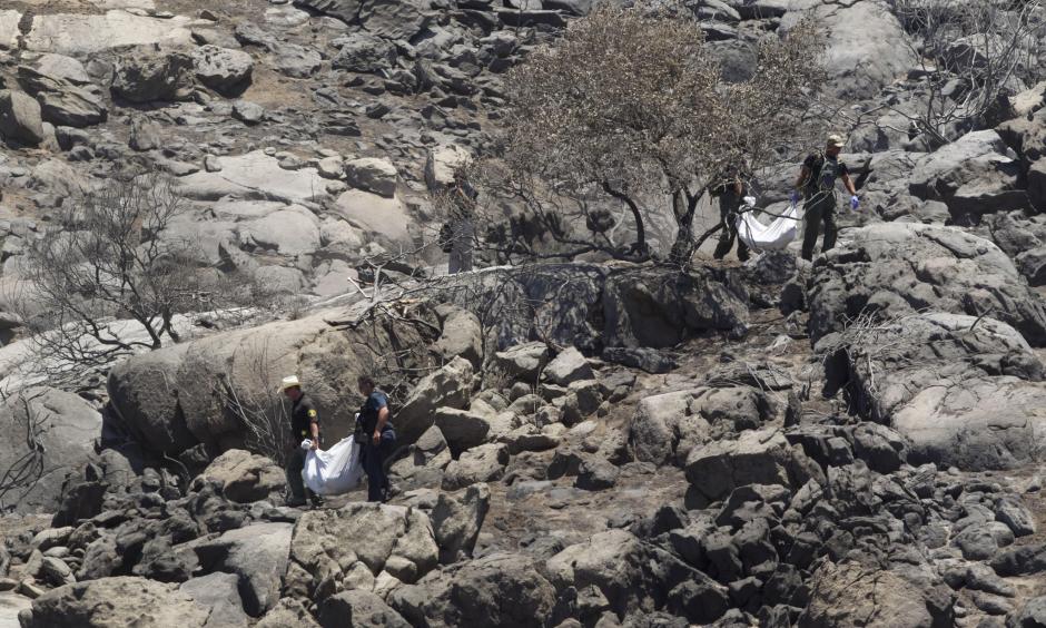 Deputies carry the remains of two victims of the Border fire down from the hillside where their bodies were discovered by neighbors. Photo: John Gibbins / San Diego Union-Tribune