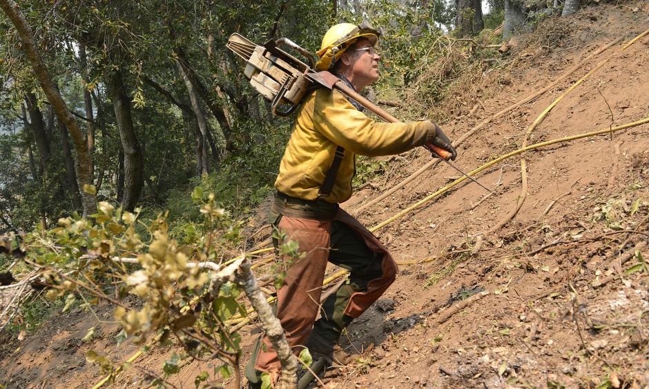 Jeff Turpin hikes up a hillside with his chain saw Saturday while cutting a fire break for the Soberanes fire. Photo: David Royal / Monterey County Herald via AP