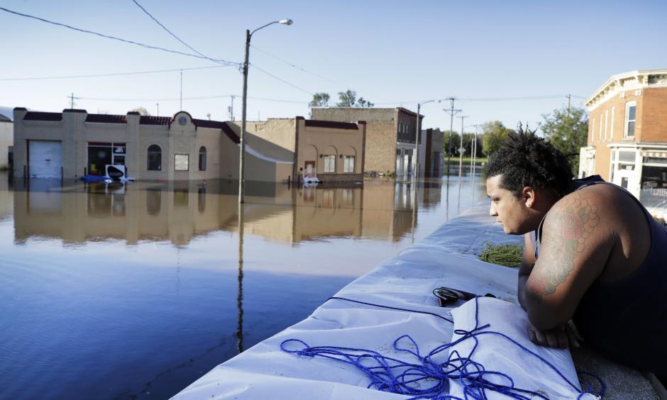 Cory Harrison stands on a flood wall as he looks over businesses flooded by the Cedar River on Sept. 27 in Cedar Rapids, Iowa. Photo: Charlie Neibergall, Associated Press)