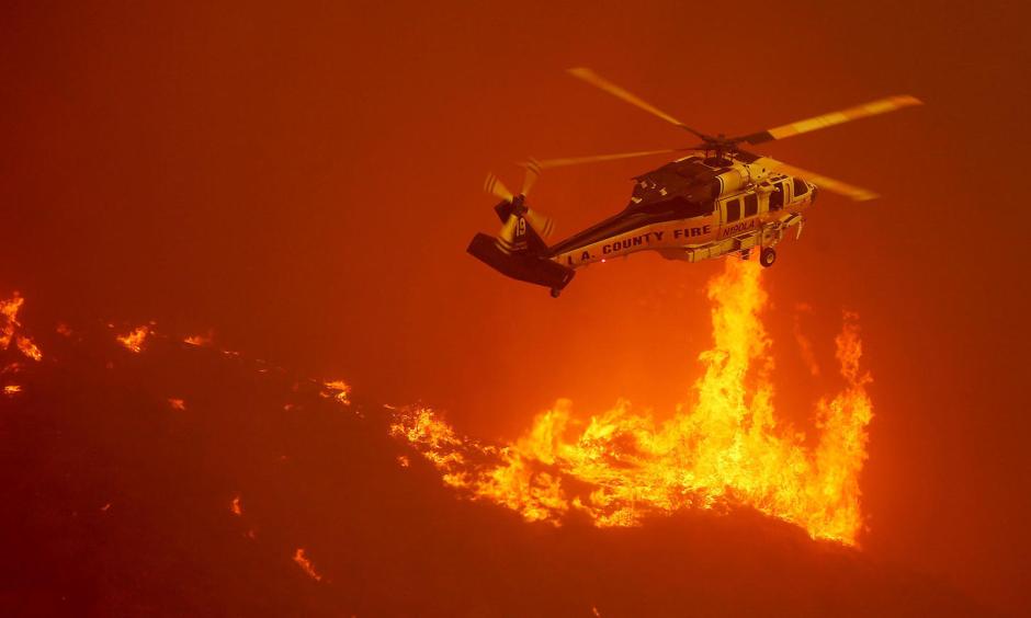 A firefighting helicopter hovers close to the flames from the Sand fire as it burns out of control along Soledad Canyon Road. Photo: Luis Sinco / Los Angeles Times