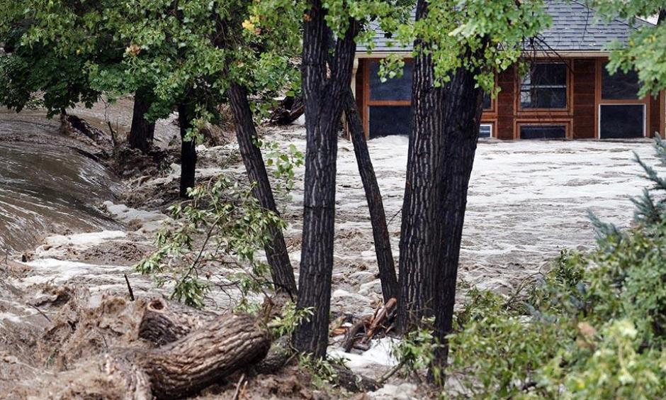 A torrent of water rushes alongside a swamped house following flash flooding near Left Hand Canyon, south of Lyons, Colo., Sept 12, 2013. Photo: Brennan Linsley, AP