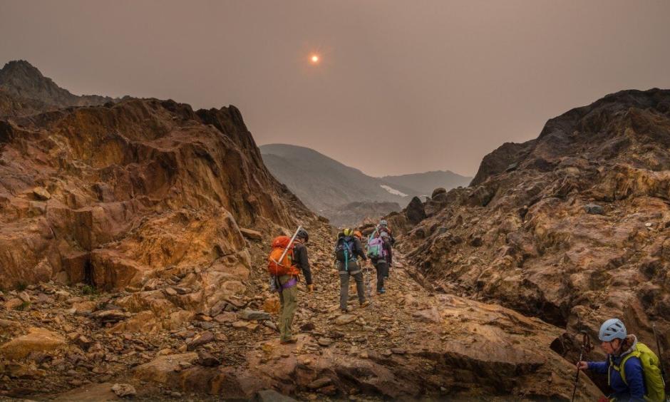 Haze from wildfire smoke obscures the sun as U of A researcher Zac Robinson leads students on a hike in B.C.'s Monashee Mountains in August 2018. Robinson is one of the editors of a new report focusing on how wildfires are affecting Canada's alpine regions. Photo: Mary Sanseverino