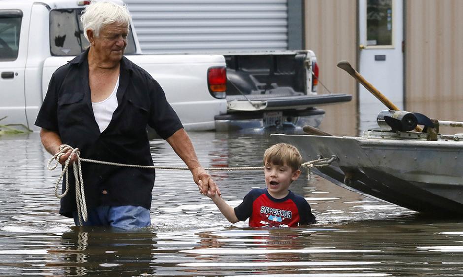 Richard Rossi and his four-year-old great-grandson, Justice, wade through water in search of higher ground after their home flooded in St. Amant, Louisiana. Photo: Jonathan Bachman / Reuters