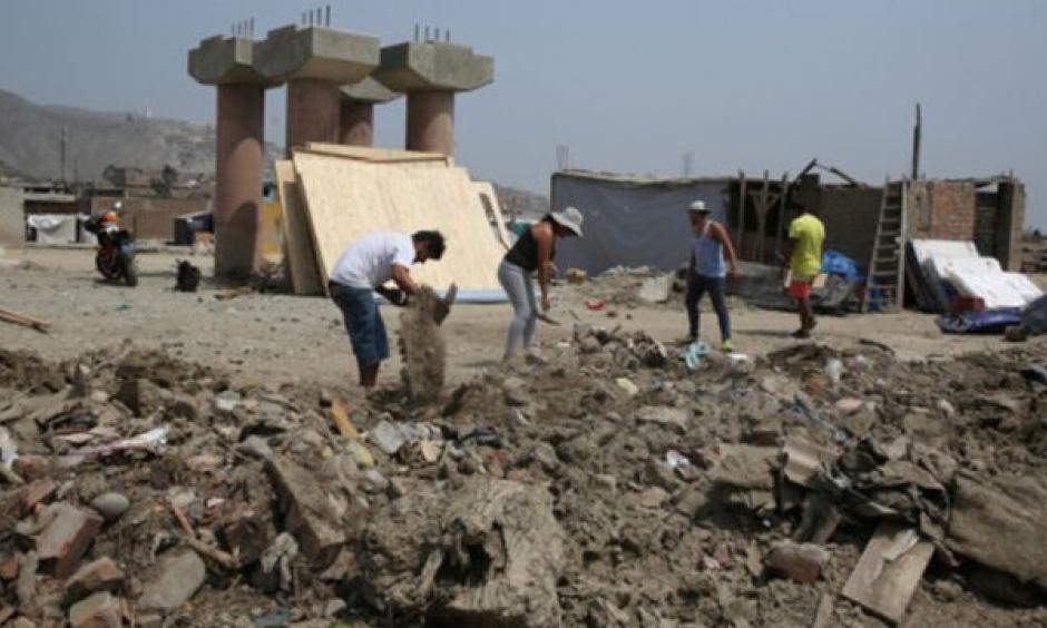 People clean a street a month after torrential rains, causing flooding and widespread destruction in Carapongo, Lima, Peru, April 18, 2017. Photo: Reuters