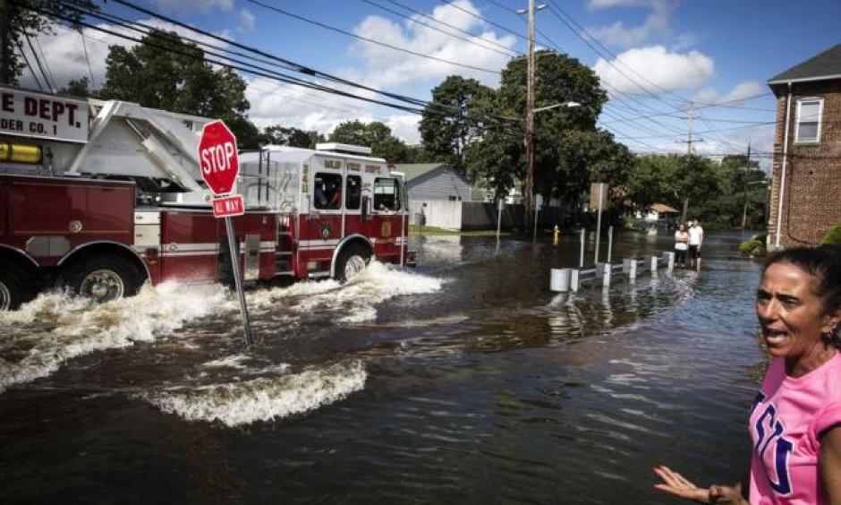 A resident watches as emergency personnel drive their truck through a flooded intersection in Islip, New York August 13, 2014. Photo: Lucas Jackson, Reuters