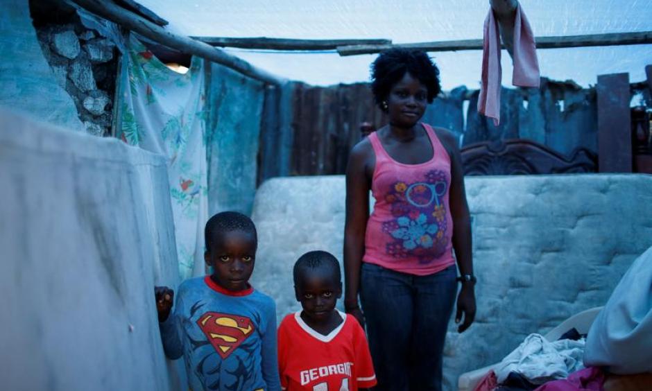 Marie Ange St Juste (R), 29, poses for a photograph with her sons, Kensley, 7 (L), and Peterley, 5, in their destroyed house after Hurricane Matthew hit Jeremie, Haiti, October 17, 2016. 'My house was totally destroyed during the storm,' said St Juste. 'I lost everything, but I was lucky that none of my children died. Now my situation is very bad, we need help.' Photo: Carlos Garcia