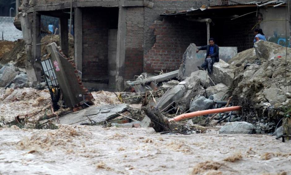 Man sits near a flooded home after the Rimac river overflowed near the Central Highway in Huarochiri, Lima, Peru, March 23, 2017. Photo: Guadalupe Pardo, Reuters
