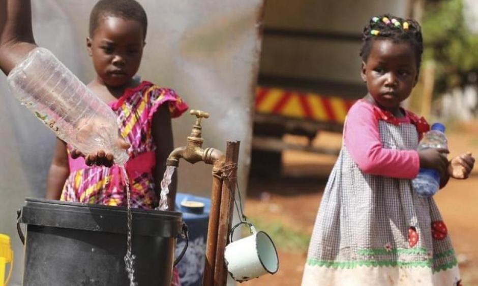 Zimbabwean children watch as their mother collects water from a communal tap in Harare, February 5, 2016. Photo: Reuters, Philimon Bulawayo