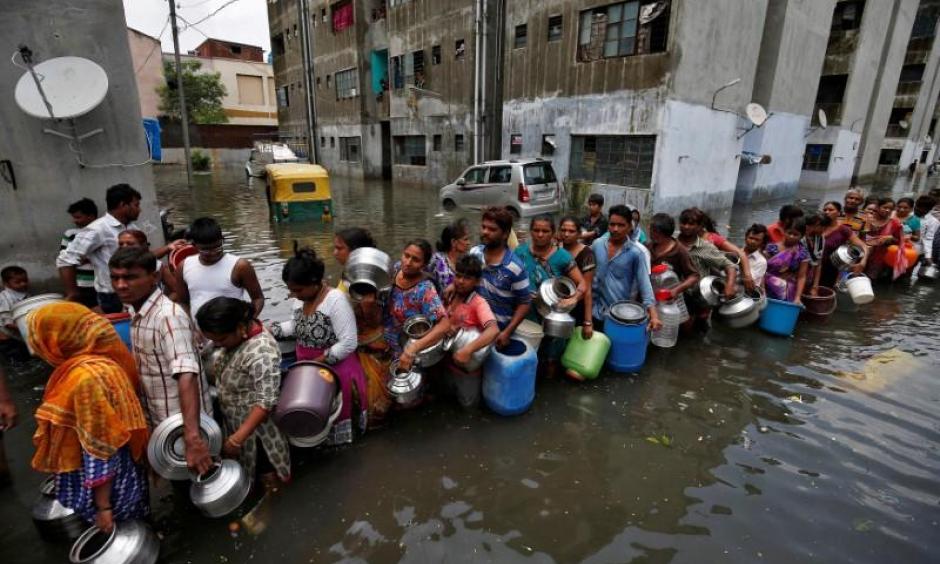 People queue to collect drinking water from a municipal tanker at a flooded residential colony in Ahmedabad, India, July 29, 2017. Photo: Thomson Reuters Foundation