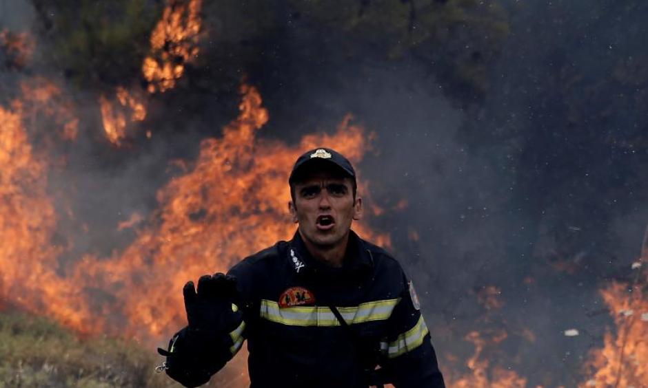 A firefighter reacts as flames rise during a wildfire near the village of Kapandriti, north of Athens, Greece, August 15, 2017. Photo: Alkis Konstantinidis