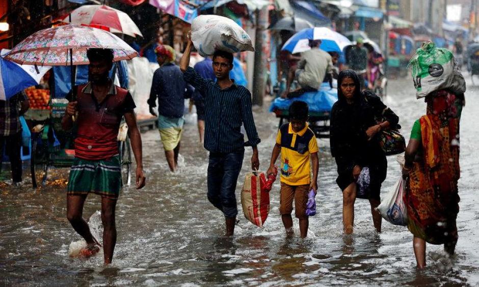 People walk on the water as roads are flooded due to heavy rain in Dhaka, Bangladesh July 26, 2017. Photo: Mohammad Ponir Hossain, Reuters