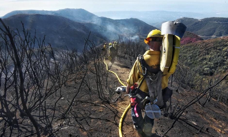 Santa Barbara County Firefighters haul dozens of pounds of hose and equipment down steep terrain to root out and extinguish smoldering hot spots in Santa Barbara on Tuesday, Dec. 19, 2017. Officials estimate that the Thomas Fire will grow to become the biggest in California history before full containment. Photo: Mike Eliason, AP