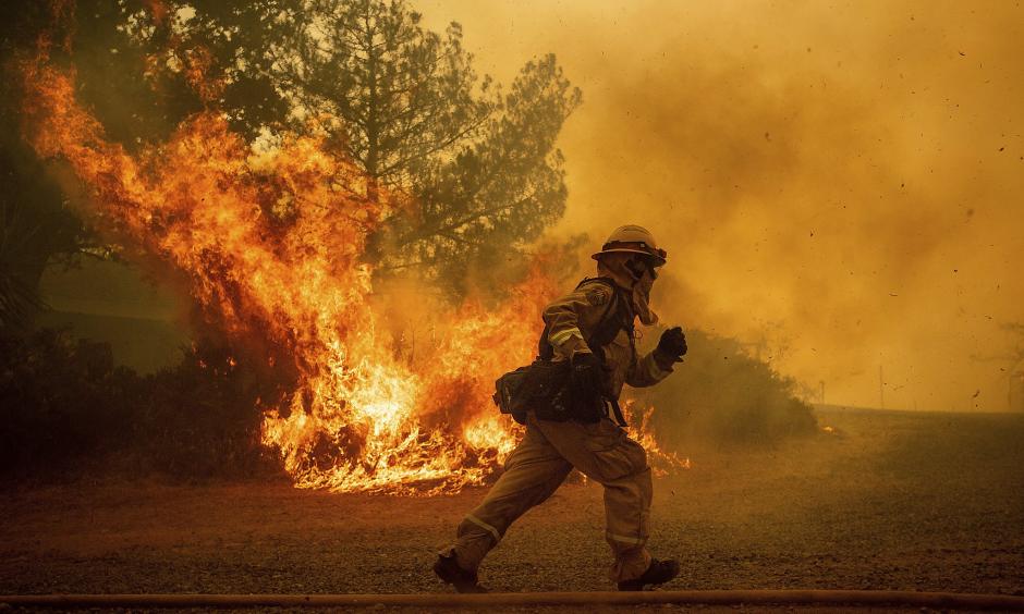 A firefighter runs while trying to save a home as a wildfire tears through Lakeport (Lake County) on Tuesday. The shift in the jet stream that’s driving the West’s stagnant hot weather is almost certainly the result of global warming, climate scientists say. Credit: Noah Berger, Associated Press