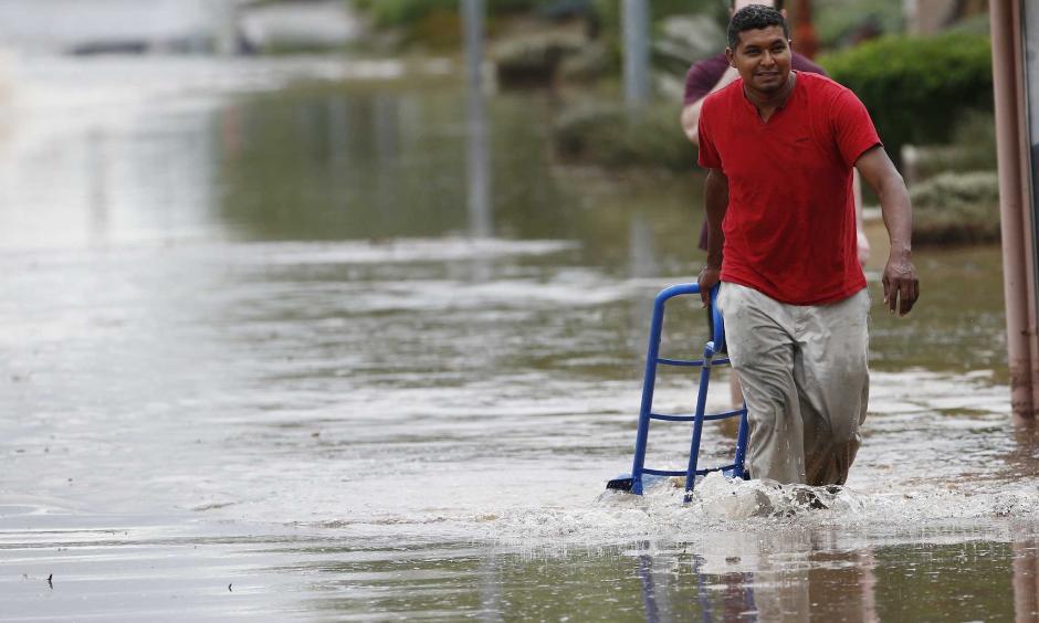 A pedestrian walks through a flooded street with a hand truck to get sand bags to deliver to local businesses during a flash flood as a result of heavy rains from tropical storm Rosa Tuesday, Oct. 2, 2018, in Phoenix. Photo: Ross D. Franklin, AP