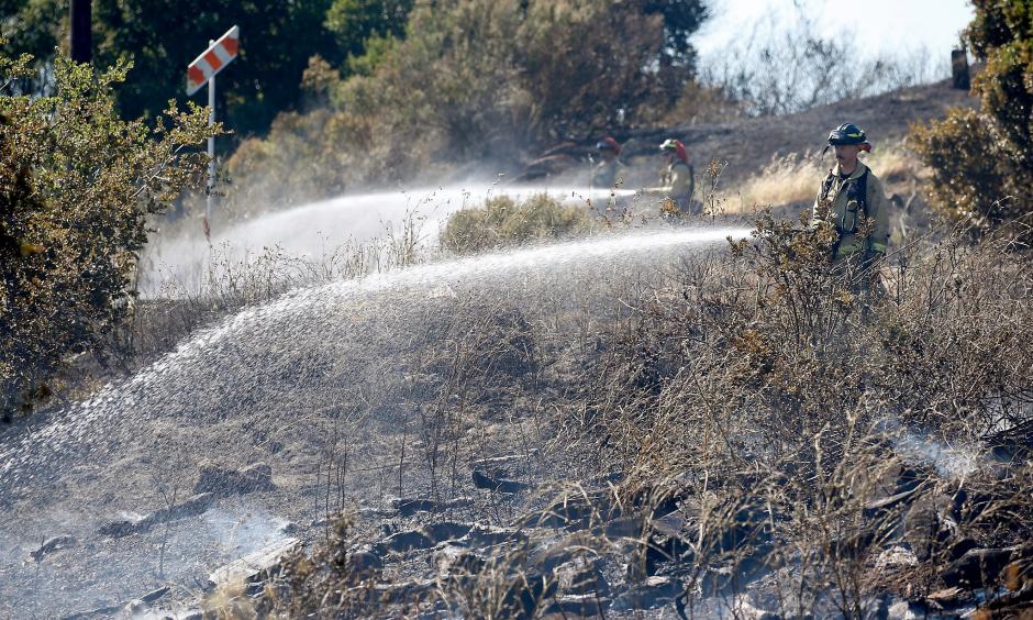 Firefighters extinguish hotspots from a four-alarm fire that consumed 24 acres on a dry hillside in Cordelia, Calif. on Friday, June 7, 2019. Photo: Paul Chinn, San Francisco Chronicle