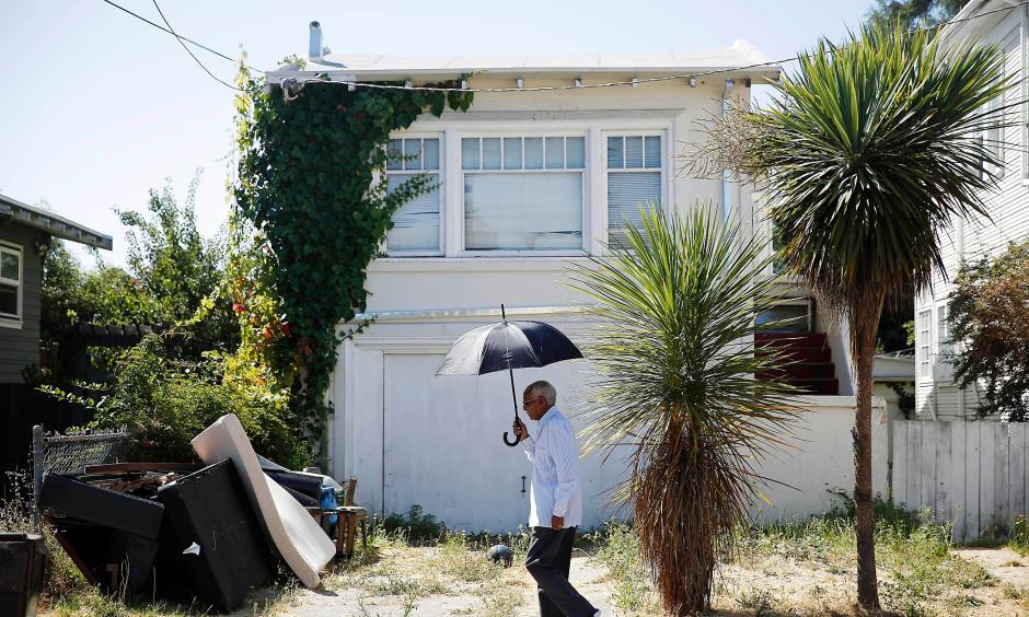 Berhane Woldeabzghi takes cover from the sun as he strolls through his Oakland neighborhood. Photo: Lea Suzuki, The Chronicle