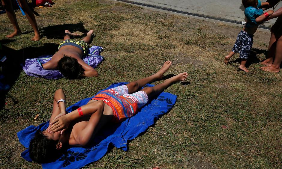 Julian Schmilinsky, 13, lower left, wipes sweat from his face while laying in the sunshine with John-Paul Schmilinsky, 12, upper left. Photo: Leah Millis, The Chronicle
