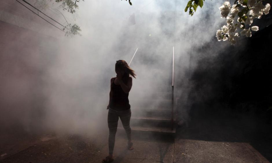 A woman walks away from her apartment as health workers fumigate as part of preventive measures against the Zika virus in Soyapango, El Salvador. Photo: Jose Cabezas, Reuters